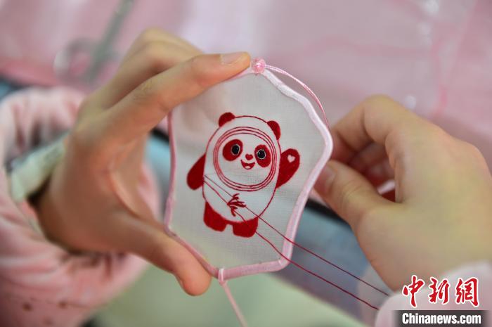 圖為一名小學(xué)生正在繡制2022年北京冬奧會(huì)吉祥物“冰墩墩”形象?！∮髟屏?攝