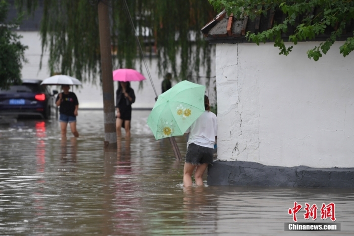 7月31日，市民行走在雨中的北京房山區(qū)瓦窯頭村。北京市氣象臺(tái)當(dāng)日10時(shí)發(fā)布分區(qū)域暴雨紅色預(yù)警信號(hào)。北京市水文總站發(fā)布洪水紅色預(yù)警，預(yù)計(jì)當(dāng)日12時(shí)至14時(shí)，房山區(qū)大石河流域?qū)⒊霈F(xiàn)紅色預(yù)警標(biāo)準(zhǔn)洪水。<a target='_blank' href='/'><p  align=