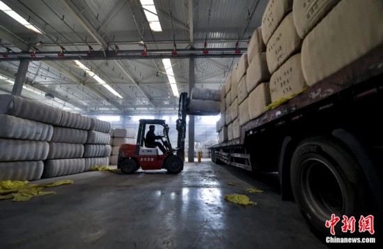 新疆喀什綜合保稅區(qū)，喀什啟路國際貿(mào)易有限公司的倉庫內(nèi)，工人正在裝載從塔吉克斯坦和烏茲別克斯坦進(jìn)口的棉花。劉新攝