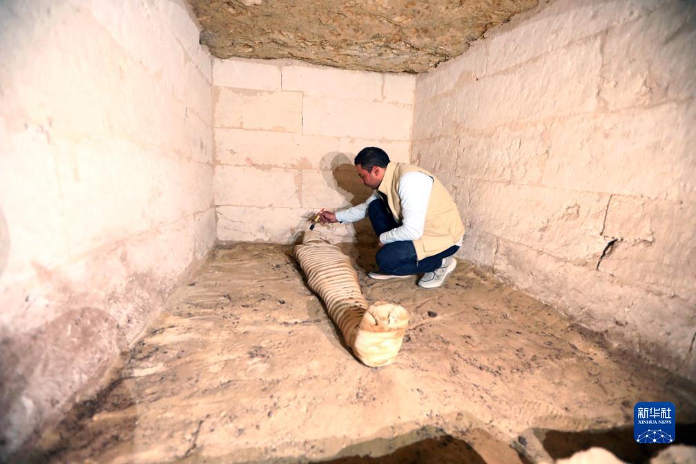 10月15日，在埃及明亞省考古現(xiàn)場(chǎng)，考古人員清理一座石鑿墓中的木乃伊。新華社發(fā)（艾哈邁德·戈馬攝）