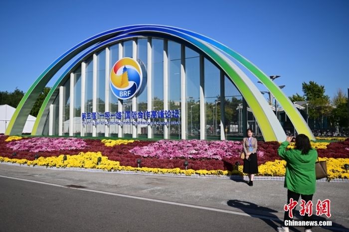 10月15日，北京，工作人員在國家會議中心外的第三屆“一帶一路”國際合作高峰論壇景觀布置前拍照留念。當日，位于國家會議中心的第三屆“一帶一路”國際合作高峰論壇新聞中心啟動試運行。據(jù)悉，第三屆“一帶一路”國際合作高峰論壇將于10月17日至18日在北京舉行。<a target='_blank' href='/'><p  align=