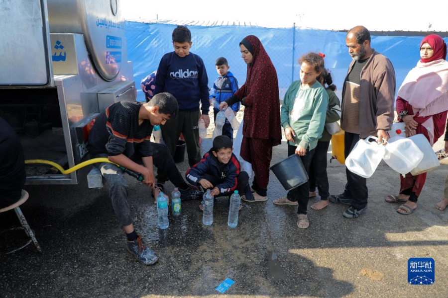 12月8日，在加沙地帶南部城市拉法一處臨時營地內(nèi)，人們排隊打水。新華社發(fā)（里澤克·阿卜杜勒賈瓦德 攝）