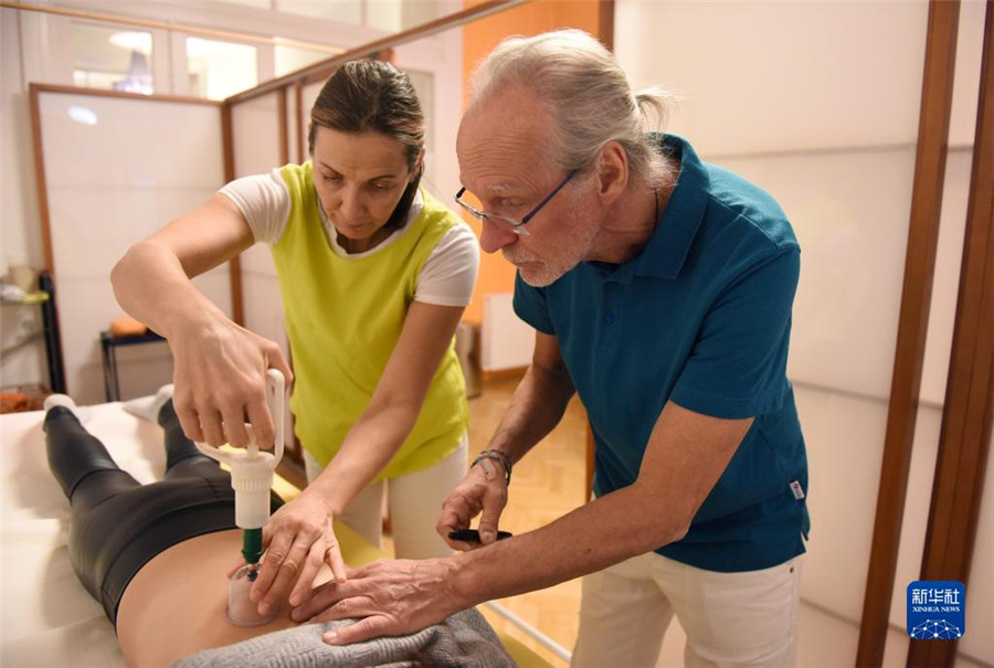 12月12日，在奧地利維也納，科格勒醫(yī)生（右）和助手在為病人進(jìn)行拔罐治療。新華社記者 賀燦鈴 攝