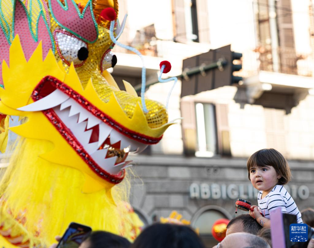 2月18日，在意大利羅馬，一名小朋友在彩妝巡游上觀看舞龍。新華社記者 李京 攝