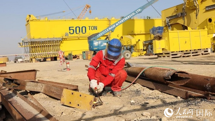 工人正在龍門吊吊裝現(xiàn)場切割金屬件。人民網(wǎng)記者管克江攝