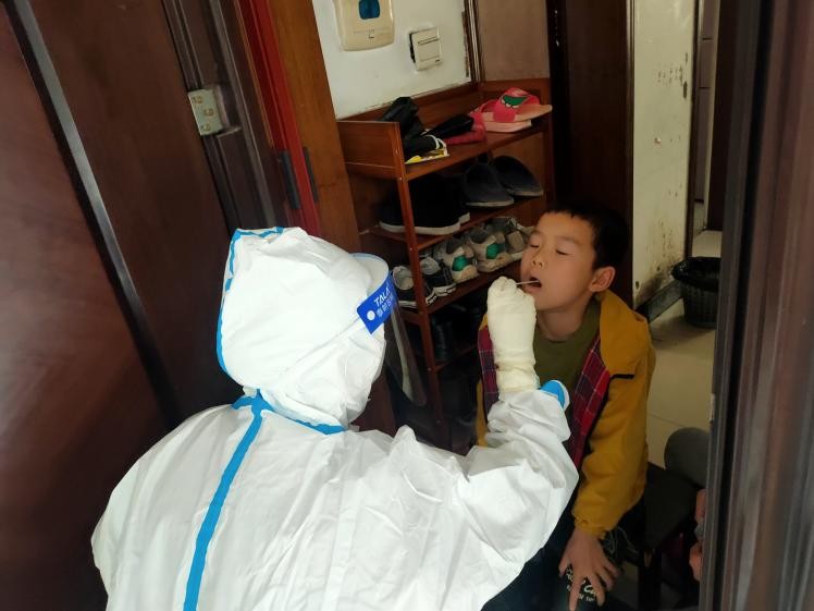 醫(yī)務(wù)工作者為封控區(qū)的居民上門采樣核酸。單位供圖