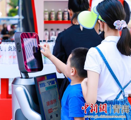 圖為一名小朋友正在和機(jī)器人“志愿者”進(jìn)行互動(dòng)。 沐聞 攝