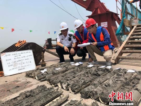 圖為勘察設計人員與海事局工作人員查看巖芯情況。　魏震 攝