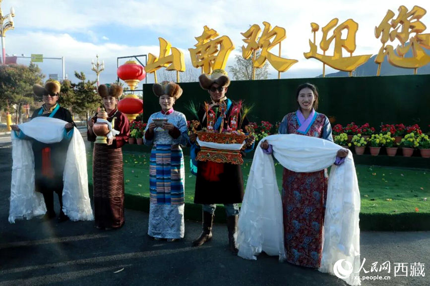 扎西曲登社區(qū)的居民在“山南歡迎您”標志前，手持潔白哈達和切瑪，列隊迎接來自區(qū)內(nèi)外的游客，用最隆重的禮儀開啟一場沉浸式藏歷新年民俗體驗之旅。人民網(wǎng)記者 吳雨仁攝