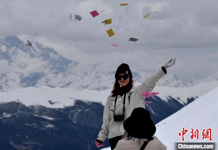 圖為5月14日，游客在西藏林芝色季拉山觀景臺(tái)拋灑“隆達(dá)”(風(fēng)馬旗，藏族民眾的一種祈福方式)?！±盍?攝