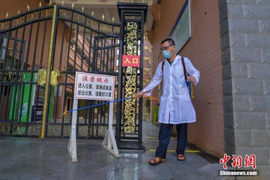 資料圖：海口經(jīng)濟學(xué)院的工作人員在學(xué)生宿舍樓入口消毒。 中新社記者 駱云飛 攝