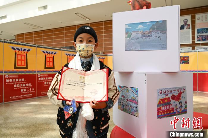 圖為一名獲獎(jiǎng)學(xué)生與自己的繪畫作品合影。　趙朗 攝