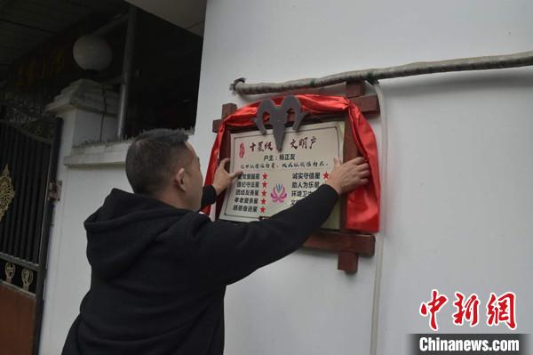 桂溪鎮(zhèn)渭溝村政府工作人員為“十星級(jí)文明戶”掛上牌匾。　楊勇 攝