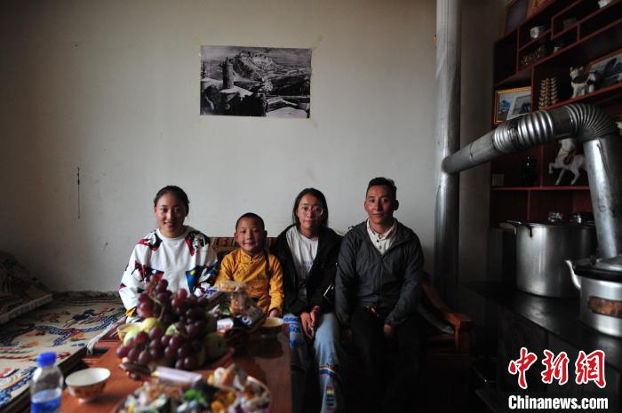 圖為8月12日，2018年7月從距那曲市色尼區(qū)城區(qū)那曲鎮(zhèn)90千米外的古露鎮(zhèn)當(dāng)桑村搬遷至城區(qū)的旦增(右一)與家人在80多平方米的新家合影(資料圖)。　張偉 攝