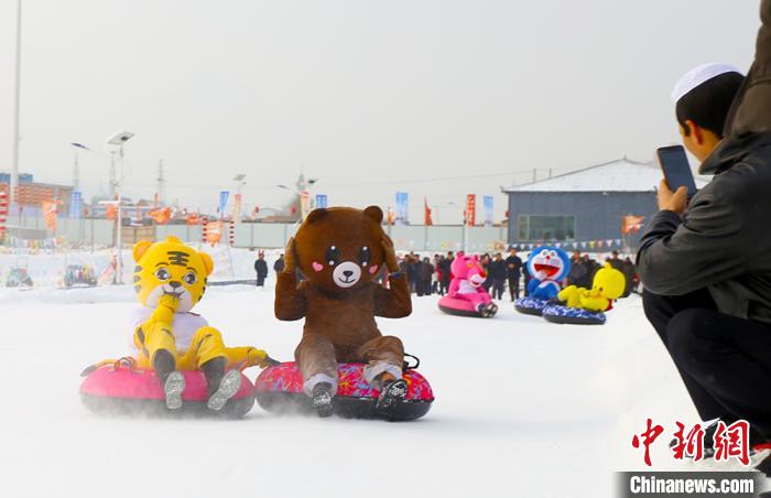 圖為臨夏市南龍鎮(zhèn)馬家莊村舉辦的鄉(xiāng)村文化旅游節(jié)上，游客穿著卡通服裝在體驗雪上飛碟項目。近年來，臨夏州形成了“春賞花、夏避暑、秋摘果、冬玩雪”的全季節(jié)旅游產(chǎn)品體系。(資料圖) 高展 攝