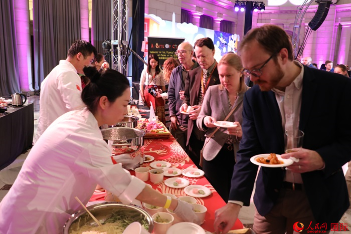 當?shù)貢r間3月7日晚，華盛頓聯(lián)合車站廣場舉行駐美使團“使館主廚挑戰(zhàn)賽”。圖為當?shù)孛癖娫谥袊古_前體驗中國美食。人民網(wǎng)記者 李志偉攝