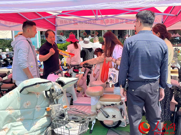 某電動(dòng)自行車品牌工作人員向消費(fèi)者介紹以舊換新相關(guān)情況。人民網(wǎng)記者 杜燕飛攝