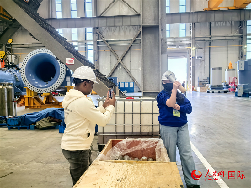 外媒記者掂量廠房內(nèi)的巨型螺栓。人民網(wǎng) 楊春燕攝