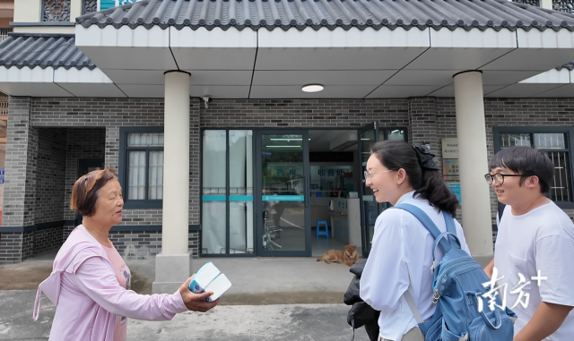 公共服務(wù)組成員王櫻潔（中）和張龍（右）在崖口村衛(wèi)生室前跟村民打招呼。