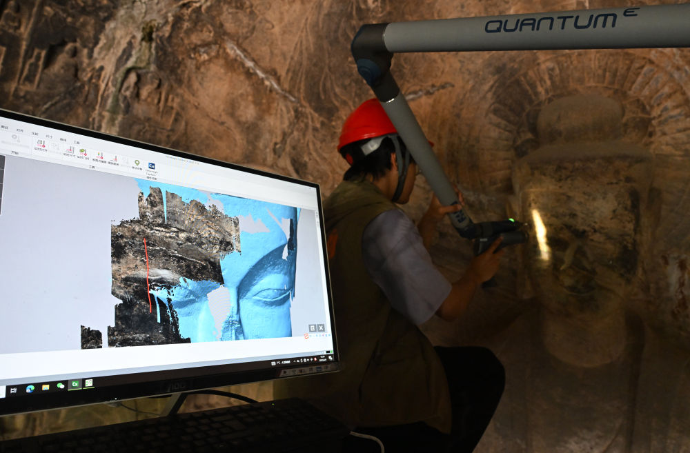 2025年4月9日，武漢大學文化遺產(chǎn)智能計算實驗室團隊成員在魏字洞使用關(guān)節(jié)臂掃描儀對佛像進行數(shù)字化掃描。圖片來源新華社