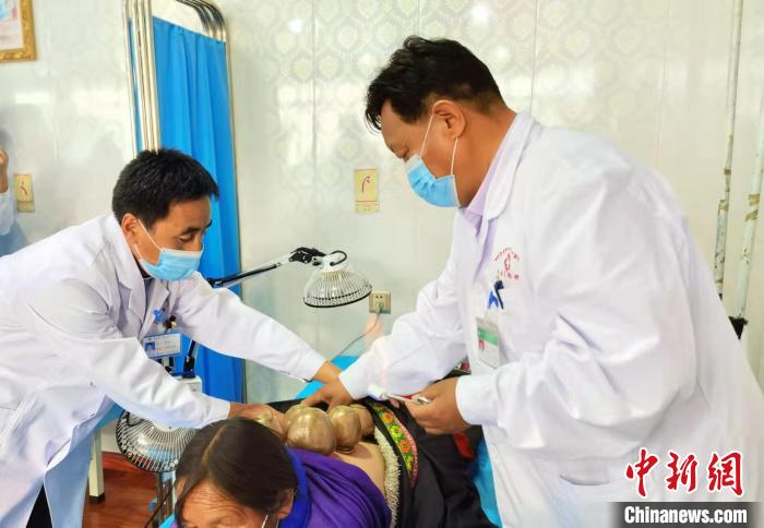 圖為看照加手把手帶徒弟加老(左一)進(jìn)行拔罐療法。　張婧 攝