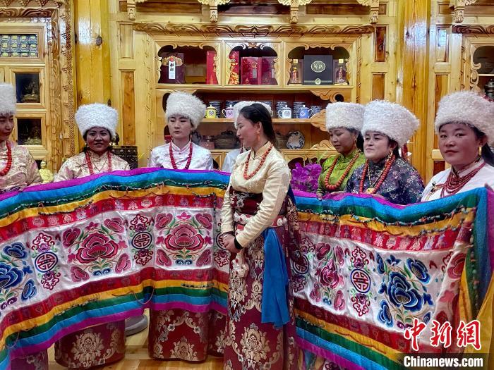 圖為女性展示村民自發(fā)繡制的“百米五彩哈達”?！±钣穹?攝