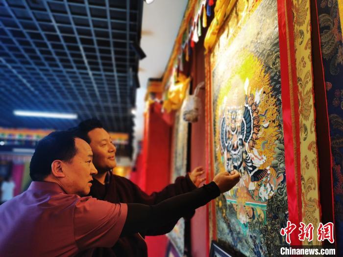 圖為久美尖措展示唐卡作品?！?zhí)砀?攝