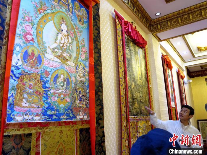 圖為完德尖措展示熱貢龍樹畫苑內(nèi)的唐卡?！?zhí)砀?攝