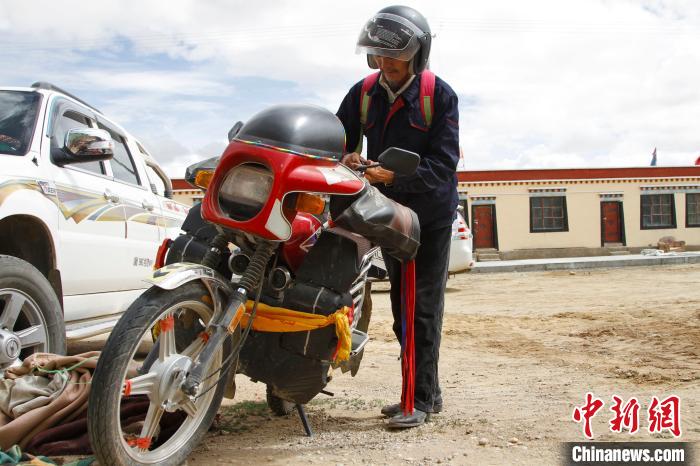 圖為白瑪準(zhǔn)備騎摩托車(chē)巡湖?！≮w朗 攝