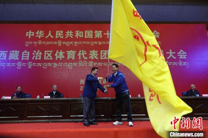 西藏自治區(qū)副主席甲熱·洛桑丹增授代表團(tuán)團(tuán)旗，西藏自治區(qū)體育局局長尼瑪次仁接旗。　冉文娟 攝