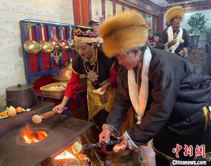 圖為人們在火上烤節(jié)日美食“結(jié)達”?！∪轿木?攝