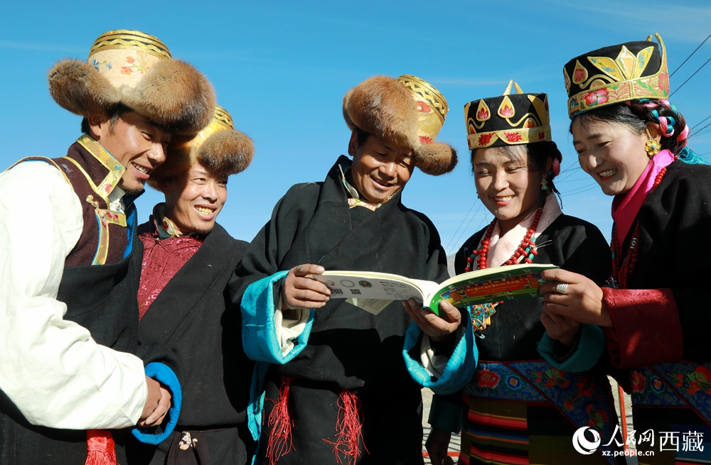 鄉(xiāng)親們身著民族盛裝，圍站在一起認(rèn)真翻看日歷，共話農(nóng)事安排與時(shí)節(jié)規(guī)律，笑容洋溢傳遞豐收期盼。人民網(wǎng)記者 吳雨仁攝